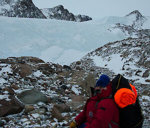 Expeditioner sitting on the ground looking at the large ice sheet