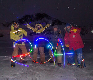 Four expeditioners standing together on the lake ice at night