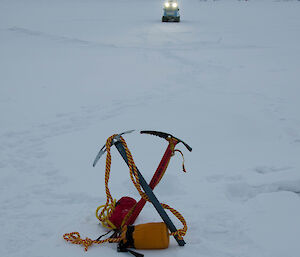 Two ice axes and throw bags in the foreground, Hägglunds driving towards camera in the background