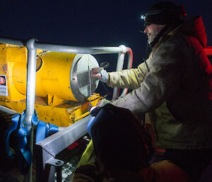 At night, two expeditioners strapping down a yellow herman nelson heater on the back of a trailer