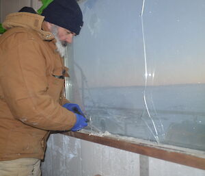 Expeditioner scraping paint off the windowsill