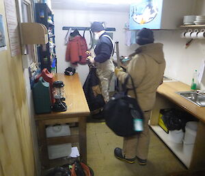 Two expeditioners leaving the hut with their bags