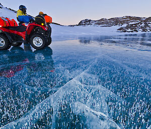 Expeditioner with a quad bike parked on a frozen clear lake