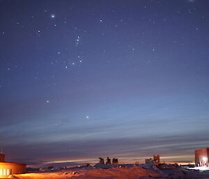 Bright stars on a clear night above station buildings — the Orion constellation features prominently