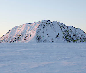 A small rocky island covered in snow, surrounded by sea ice