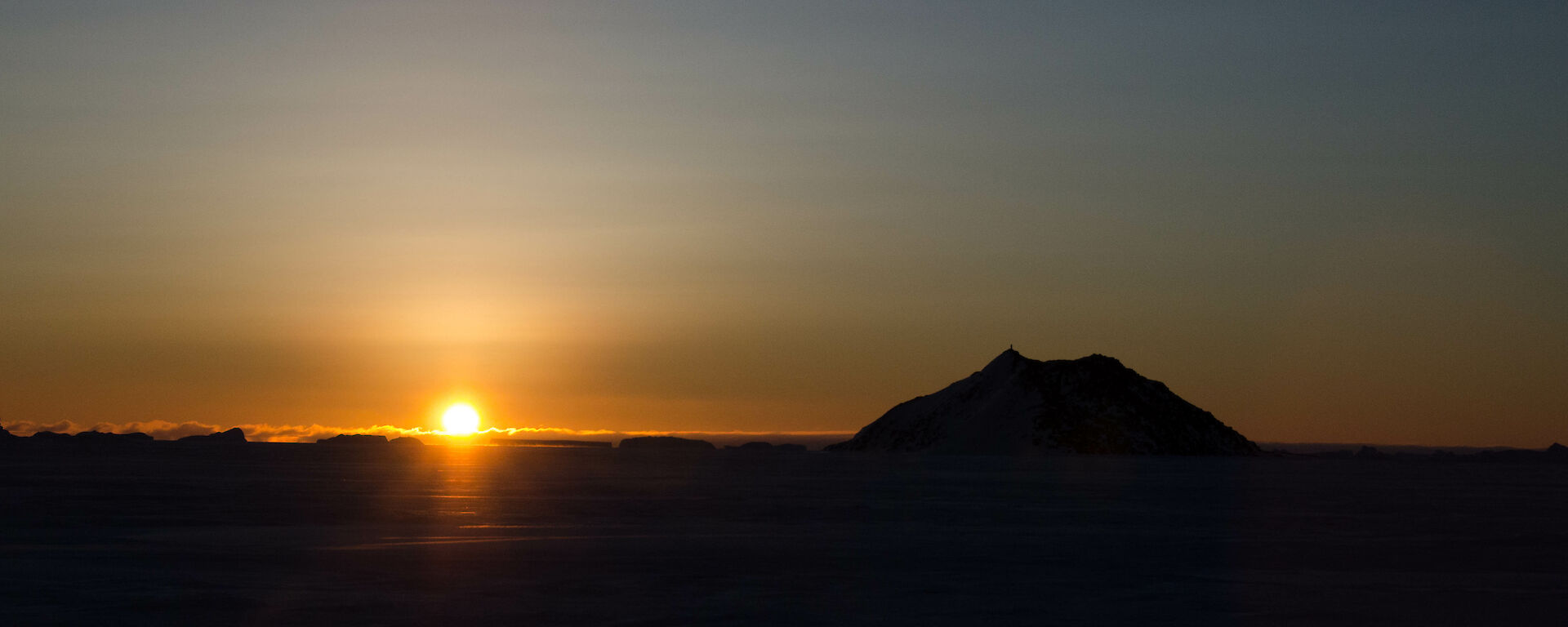 Bright yellow sunset over the sea ice and small rocky islands