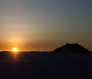 Bright yellow sunset over the sea ice and small rocky islands