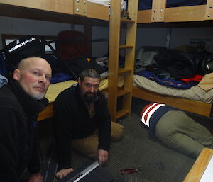 Three expeditioners sitting on the floor of a hut with carpet tiles