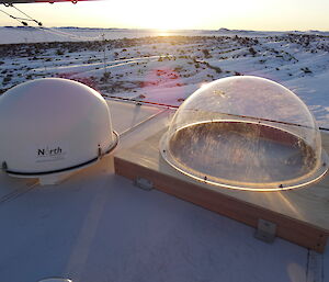 One white and one clear dome on the roof of a hut