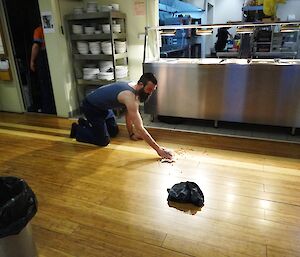 Expeditioner kneeling on the floor wiping up baked beans