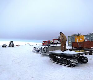 Expeditioner on the back of a sled filming the arrival of a fire hagglund