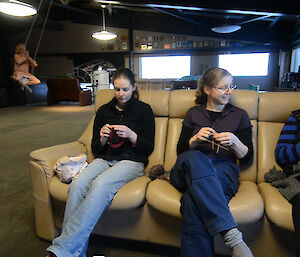 Three expeditioners sitting on a lounge knitting