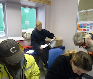 Four expeditioners in the radio comms room waiting for further information