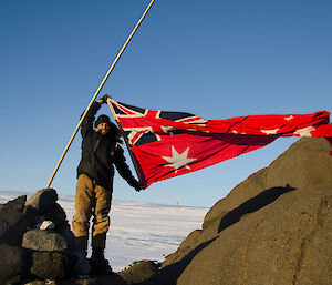Expeditioner holding a flag, flag flapping in the breeze.