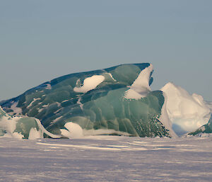 Bright green iceberg amoungst white ice bergs