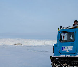 Expeditioner with her head through the roof of a hagglund taking photos