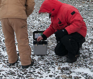 Two expeditioners with a small grey case containing a HF radio