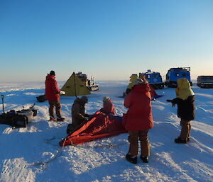 Expeditioners erecting red tents on the icy plateau