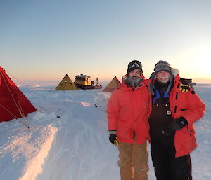 Two expeditioners standing in front of a row of tents