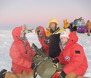 Expeditioners kneeling on the ice with a folded tent