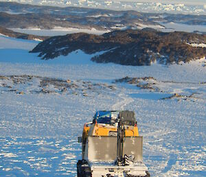Yellow hagglund on the plateau driving down the hill towards the islands