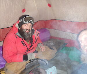 Two expeditioners in their sleeping bags in an icy tent