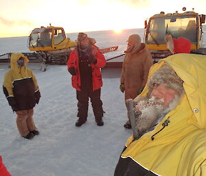 Expeditioner taking a photo of himself with a frozen beard with a few friends in the background