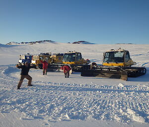 Four large vehicles parked side by side on the snow