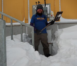 Expeditioner with a shovel standing next to the exposed door