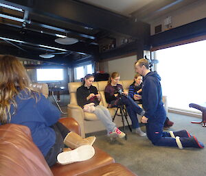 Male on his knees with his camera aimed at a few females knitting