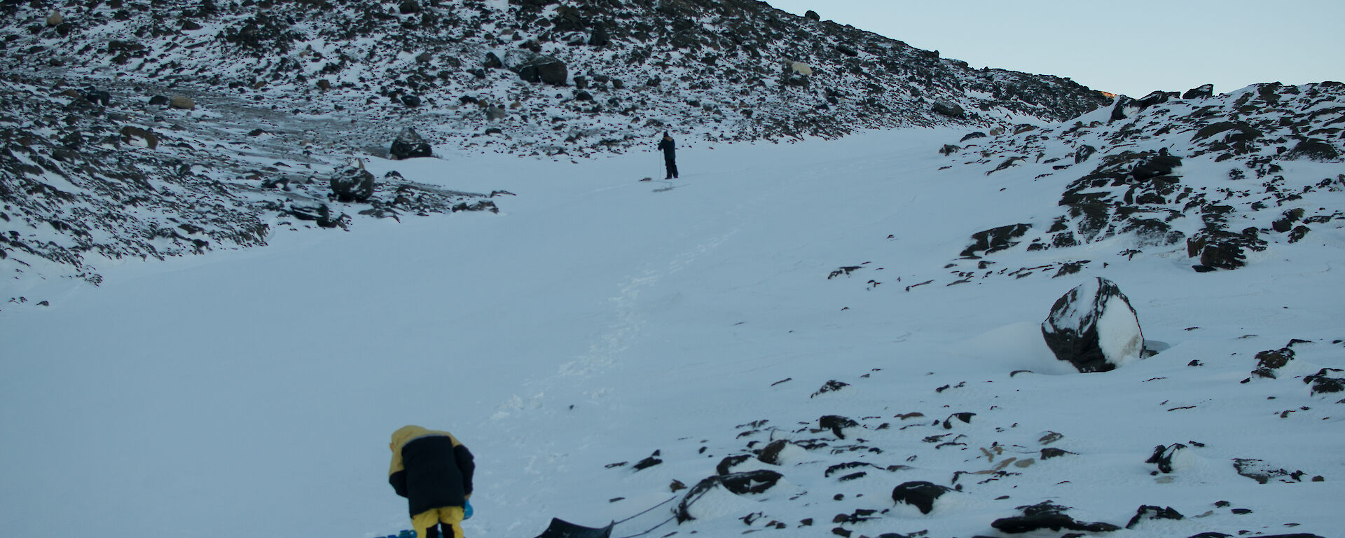 Person placing container of water on a sled in a snow filled valley