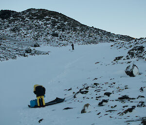 Person placing container of water on a sled in a snow filled valley