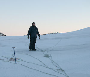 Expeditioner standing at the top of the gully with rope laid out on the snow