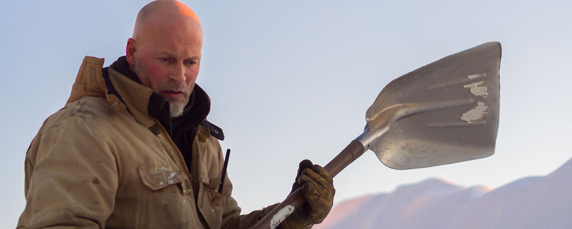 Expeditioner on snow slope with a shovel