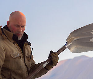 Expeditioner on snow slope with a shovel