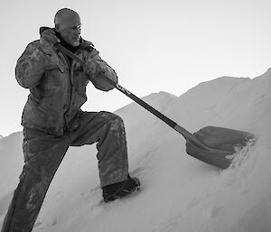 Expeditioner on a snow slope with a shovel