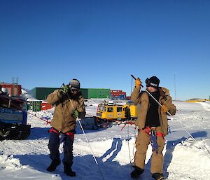 Two expeditioners attached to a hagglunds by rope probing the ground with a large stick