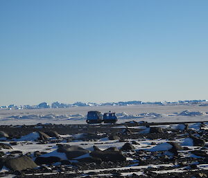 Blue Hägglunds parked on the sea ice, icebergs in the background