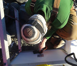 View looking down, top of expeditioners head whilst he’s connecting wires to the solar panel