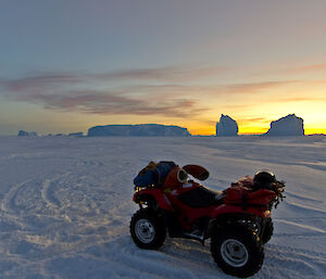 Quad bike with no rider on the sea ice, sun setting in background