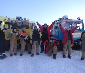 Eight expeditioners standing in front of two hagglunds