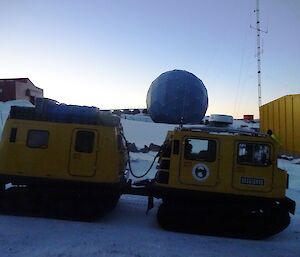 Yellow Hägglunds driving past the large satellite dome