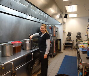 Chef standing at the stove stirring a large pot with a wooden spoon