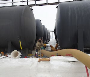 Expeditioner standing amongst 12 large fuel tanks adjusting a small generator.