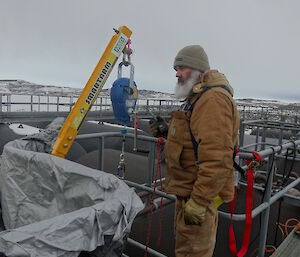 Expeditioner in harness standing on a raised platform above the fuel tanks