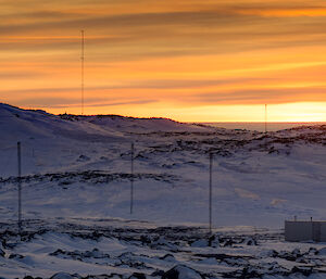 Bright yellow and orange sunset over rock and snow