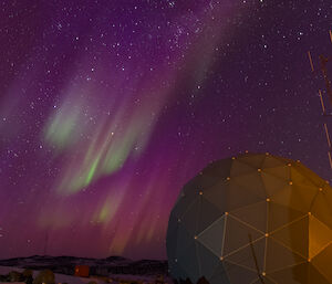 Purple and green aurora above satelite dome