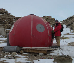 Expeditioner at the door of a red round hut