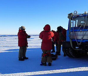 Expeditioners on the ice alongside Hägglunds