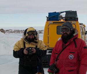 Two expeditioners standing next to the Hägglunds with the cameras ready
